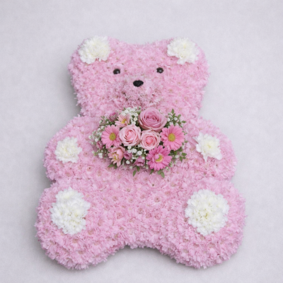 Large Teddy Bear - At Sarah Coxon Floral Design we are delighted to present this product available for flower delivery in Mid and North Norfolk. 

This specialised tribute is a Large Teddy Bear and is based in pink chrysanthemeums. The spray on the Teddy is a small cluster of Roses and Gypsophillia, and the Paws and Ears are white carnations. The Bear comes complete with a Ribbon and bow around the neck and if you would like you can have a ribbon Sash across the middle (as shown) with silver letters.

This can come in a variety of colours, please specify the colour of the ribbon and flowers you would like.

Please add the wording you would like on the ribbon sash if applicable in the special requests box.

This stunning floral display has been arranged in water retaining foam (oasis) to ensure maximum freshness. 

We deliver directly to all of the local funeral directors and will contact them to confirm a delivery time. 

Our flowers at Sarah Coxon Floral Design arrive fresh from the Dutch auctions every day so you can be rest assured we are using the best quality of flowers available.