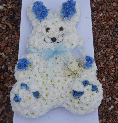 Bunny Rabbit - At Sarah Coxon Floral Design we are delighted to present this product available for flower delivery in Mid and North Norfolk. 

This specialised tribute is a cute Bunny Rabbit and is based in white chrysanthemeums. The spray on the Rabbit  is a small cluster of Roses and Gypsophillia, and the Paws and Ears are sprayed blue (or pink) carnations and Roses. The Rabbit comes complete with a Ribbon and bow around the neck.

You can choose the colour of the ears and paws, please specify the colour of the ribbon and flowers you would like.

This stunning floral display has been arranged in water retaining foam (oasis) to ensure maximum freshness. 

We deliver directly to all of the local funeral directors and will contact them to confirm a delivery time. 

Our flowers at Sarah Coxon Floral Design arrive fresh from the Dutch auctions every day so you can be rest assured we are using the best quality of flowers available.
