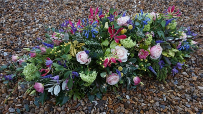 Cottage Garden Spray - This is a natural looking spray which definitely has the cottage garden look. It is designed to rest on top of a casket. It contains a variety of mixed flowers in mixed colour scheme of lime green, purple, cerise/red, pink and a touch of yellow.

 

This stunning spray includes Gloriosa, Garden-style Roses, Clematis and Hypericum together with other seasonal flowers and foliages which can be found in the garden to enhance and complement the style of this beautiful floral tribute.

 

Please note due to the nature of this spray, the flowers are all seasonal and if they are not available, we will use similar flowers which will not alter the design, colour or beauty of this spray.

 

The Cottage Garden Spray has been arranged in water retaining foam (oasis) to ensure maximum freshness and is available in 3 sizes.

 

Standard size is 3ft

 

Deluxe size is 4ft

 

Luxury size is 5ft

 

 

 

We deliver directly to all of the local funeral directors and will contact them to confirm a delivery time and to ensure we make the correct size if a full sized spray is ordered.

 

Our flowers at Sarah Coxon Floral Design arrive fresh from the Dutch auctions every day so you can be rest assured we are using the best quality of flowers available.

 

At Sarah Coxon Floral Design we are delighted to present this product available for flower delivery in Mid and North Norfolk.