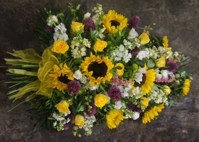 Country Sheaf Spray - This is a sheaf spray, which, although it gives the appearance of a tied bunch of flowers, it is arranged in water retaining foam (oasis) to ensure maximum freshness.

 

This pretty sheaf spray includes Sunflowers, Roses, Lisianthus and Stocks together with other seasonal Cottage garden style flowers and foliages which complement the style of this beautiful floral tribute. It is finished with an organza bow wrapped around the stems.

 

The Country Sheaf Spray is available in 3 sizes.

 

Standard size is 2ft

 

Deluxe size is 2 ½ ft

 

Luxury size is 3ft

 

 

 

If you would like an alternative colour scheme, please indicate this in the request box when you order.

 

 

 

We deliver directly to all of the local funeral directors and will contact them to confirm a delivery time and to ensure we make the correct size if a full sized spray is ordered.

 

Our flowers at Sarah Coxon Floral Design arrive fresh from the Dutch auctions every day so you can be rest assured we are using the best quality of flowers available.

 

At Sarah Coxon Floral Design we are delighted to present this product available for flower delivery in Mid and North Norfolk.